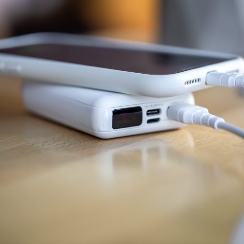 The smartphone is charged from a small white power bank via a cord, close up.